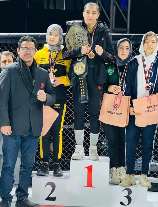 Eman Falcon Khan stands on the podium after winning the flyweight belt at the 2023 National Fighting Tournament (NFT).