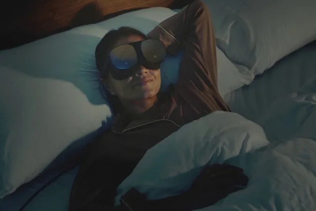 A person lying in bed wearing the HTC Vive Flow standalone VR headset and getting ready for sleep.