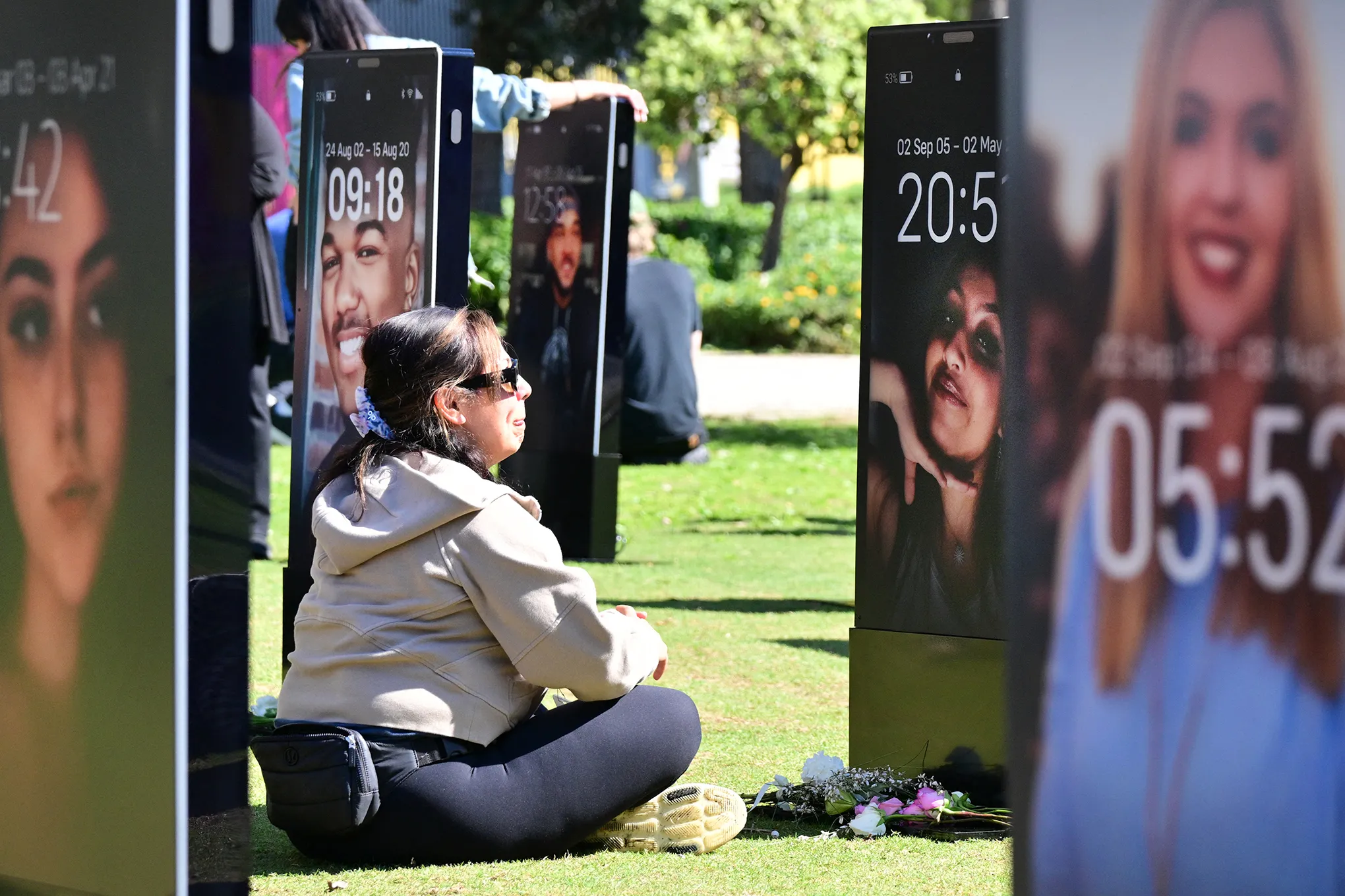 ایک خاتون آئی فون کی ایک بڑی تصویر کے سامنے غمزدہ بیٹھی ہے جس میں ایک مردہ بچے کی تصویر ہے۔