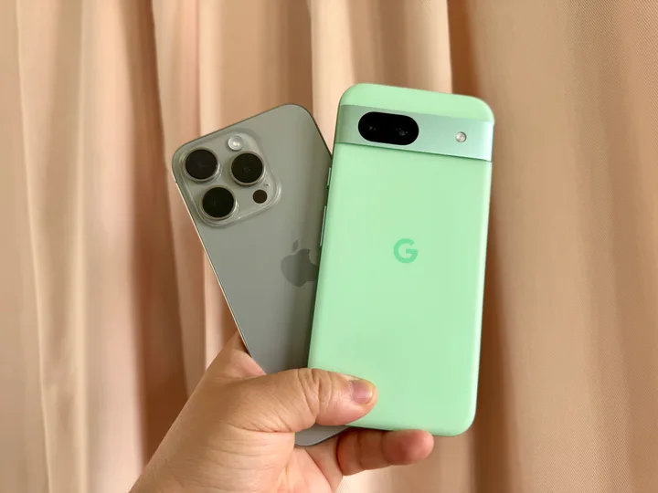 He holds an iPhone 15 Pro (left) and a Google Pixel 8a in his hands.