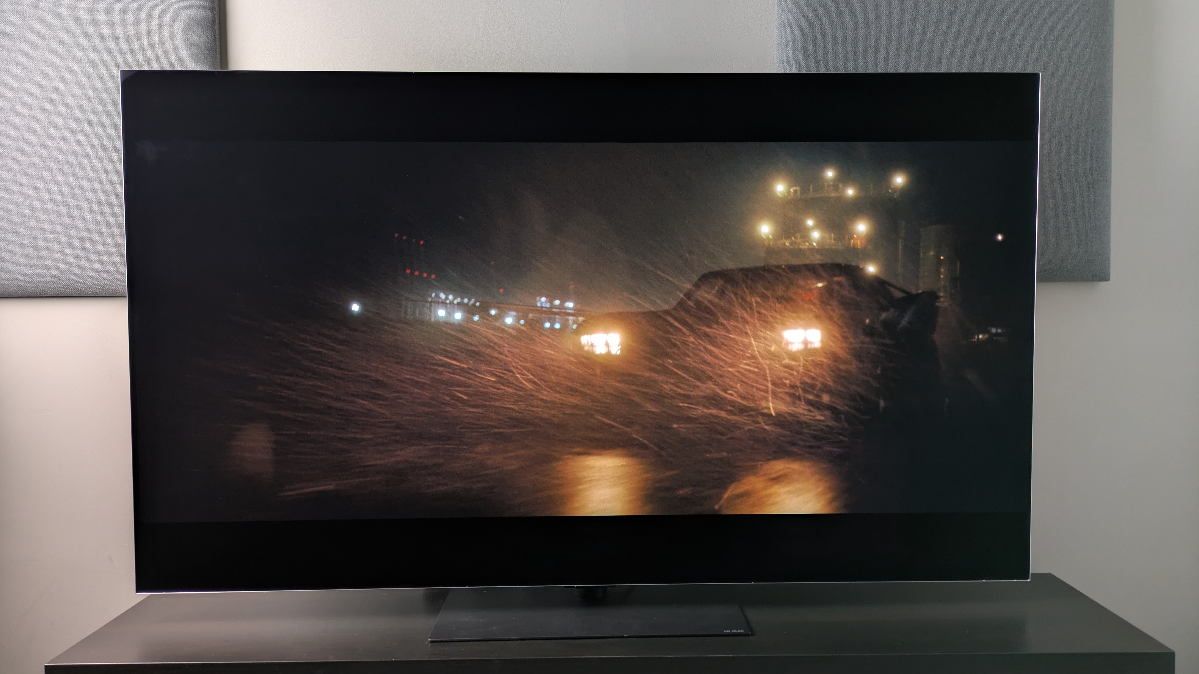 LG G6 اور Batmobile Batman فلم دکھا رہے ہیں بارش میں سڑک پر دوڑ رہے ہیں۔ روشن ہیڈلائٹس گہرے سیاہ بیک گراؤنڈ ٹون کا مضبوط کنٹراسٹ فراہم کرتی ہیں۔