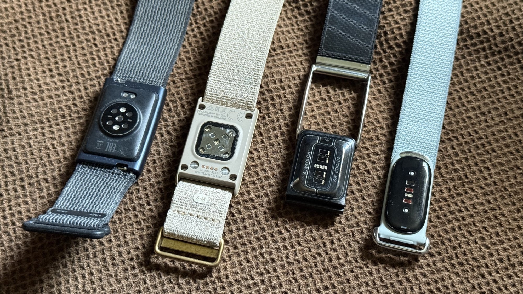 سائز کے موازنہ کے لیے Amazfit Helio، Polar Loop، Whoop MG، اور Fitbit Air ساتھ ساتھ۔