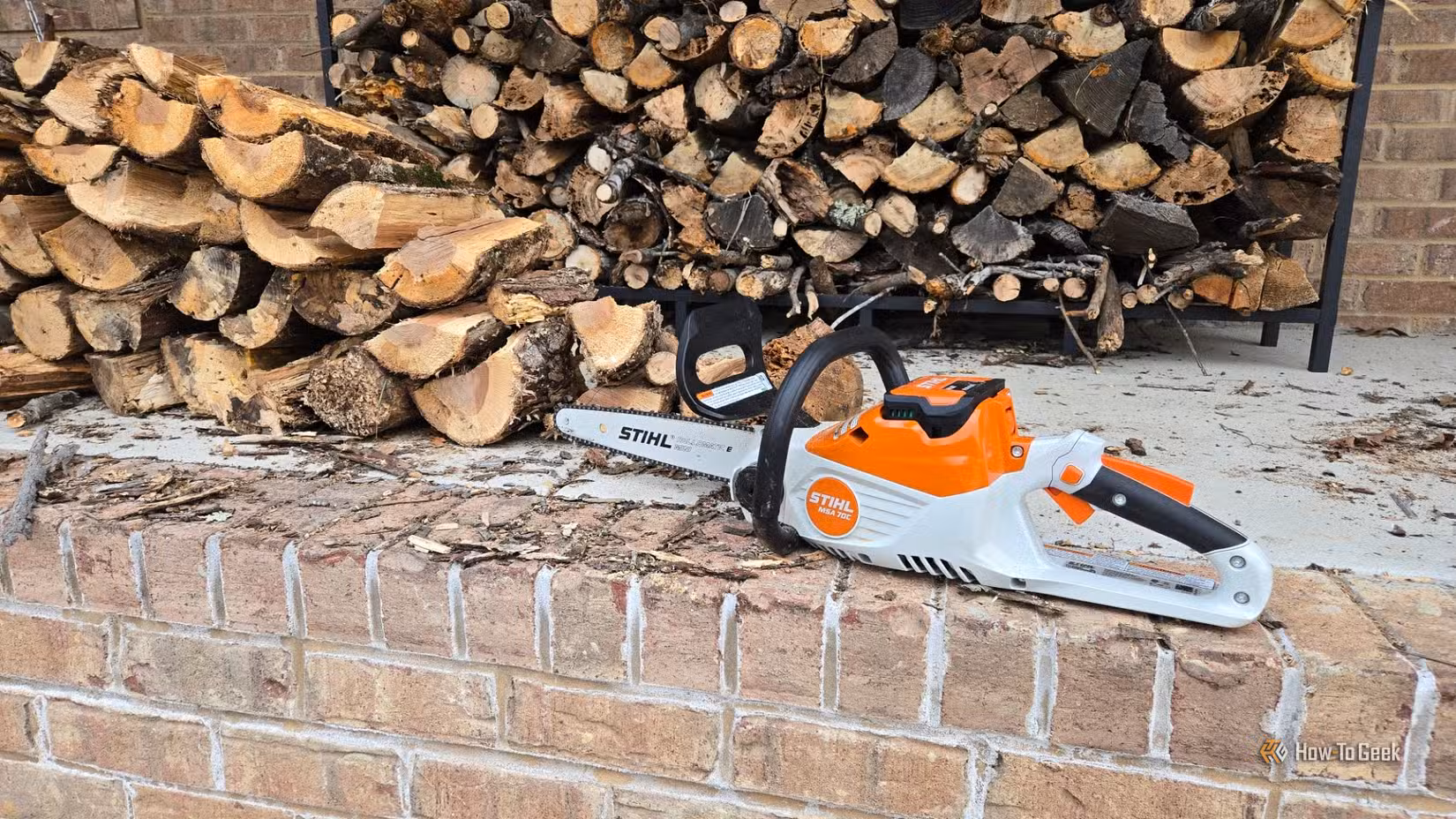 لکڑی کے دو ڈھیروں کے سامنے Stihl MSA 70 C چینسا۔