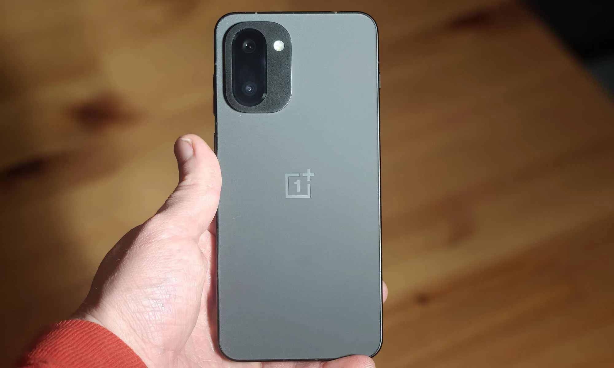 OnePlus 15R کا پچھلا حصہ ایک آدمی کے ہاتھ میں پکڑا ہوا ہے۔