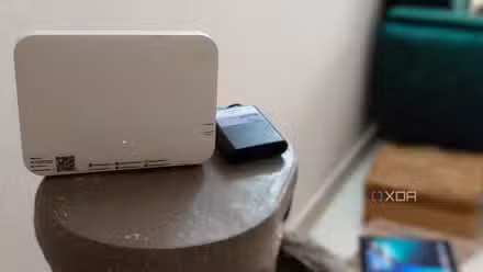سرمئی سطح پر منی UPS کے ساتھ سفید Wi-Fi روٹر