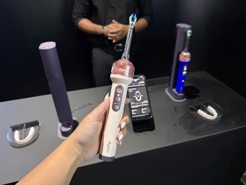 IFA برلن 2026 سے اعلی ٹیکنالوجی کے رجحانات 8 گلابی Dyson Camerajet ٹوتھ برش پکڑے ہوئے ایک ہاتھ۔